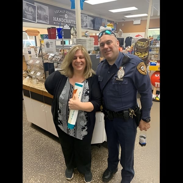 A smiling woman and a police officer pose inside Ana's Corner Store deli.