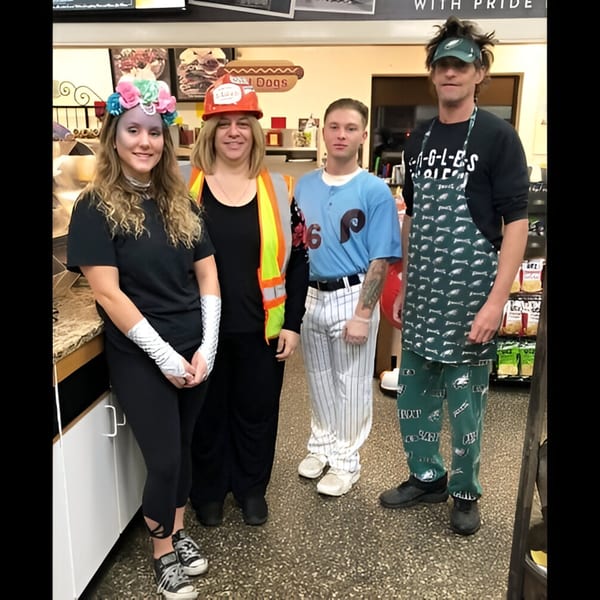 Four Ana's Corner Store employees in Halloween costumes, including a construction worker and baseball player.