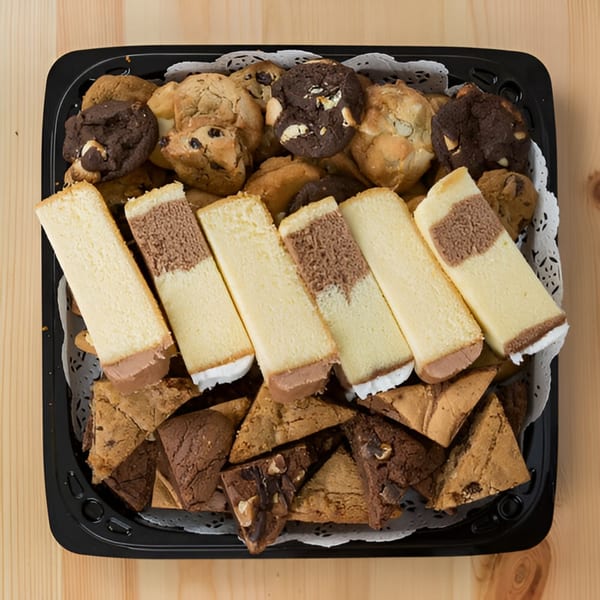 A black tray filled with assorted cookies, brownies, and cheesecake slices from Ana's Corner Store.