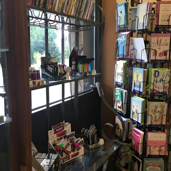 A deli interior with a window view, greeting card racks, and various small items on display.