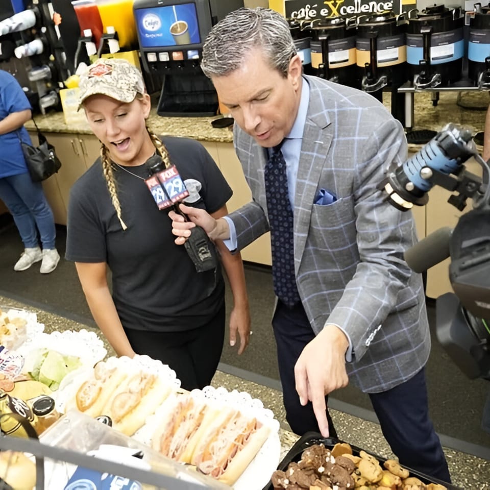 A reporter interviews a deli worker about sandwiches and cookies at Ana's Corner Store.