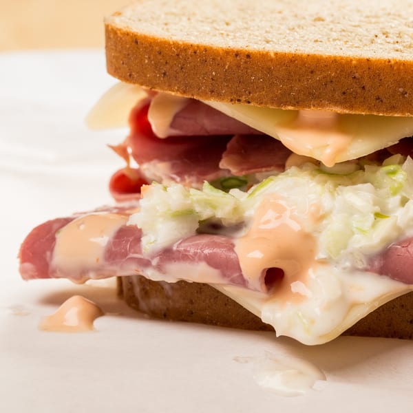 Close-up of a deli sandwich with corned beef, Swiss cheese, coleslaw, and Russian dressing.