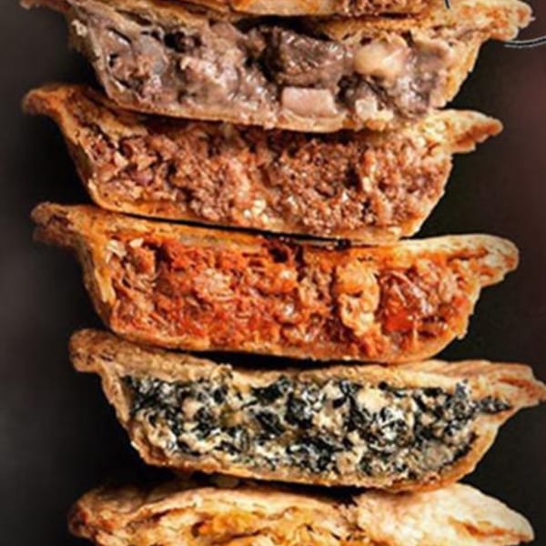 A stack of five savory Ana's Corner Store deli pies, each with a different filling.