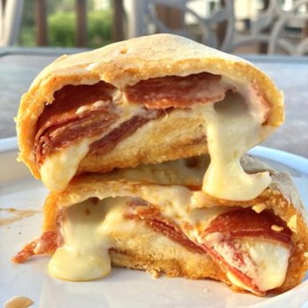 A sliced pepperoni and cheese stromboli from Ana's Corner Store, with melted cheese oozing out.