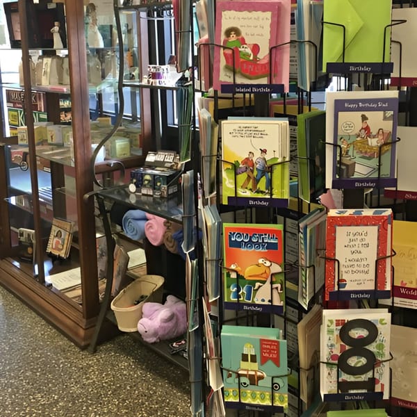 A display rack filled with various greeting cards, including birthday and belated birthday cards.