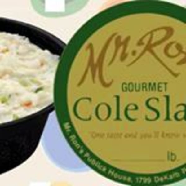 A black bowl of coleslaw next to a green and yellow label for "Mr. Ron's Gourmet Cole Slaw."