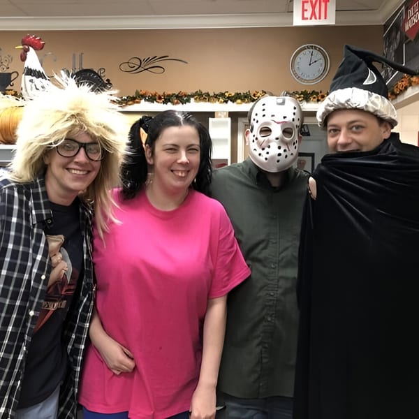 Four Ana's Corner Store employees in Halloween costumes, including a wizard and Jason Voorhees.